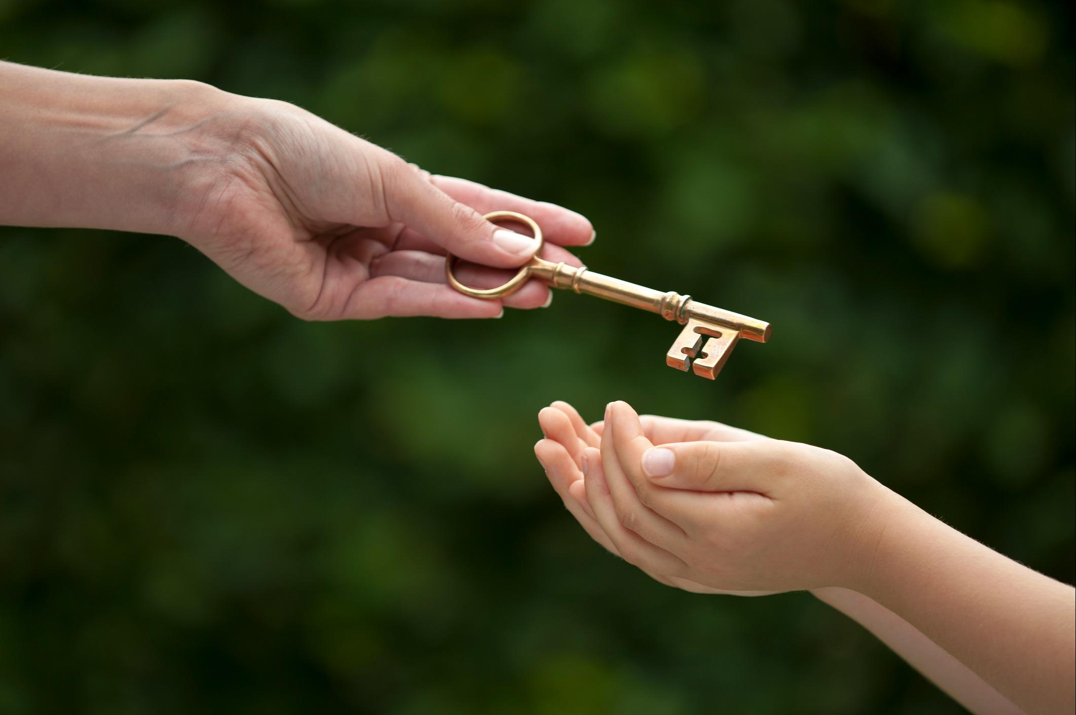 A hand passing a key to another hand