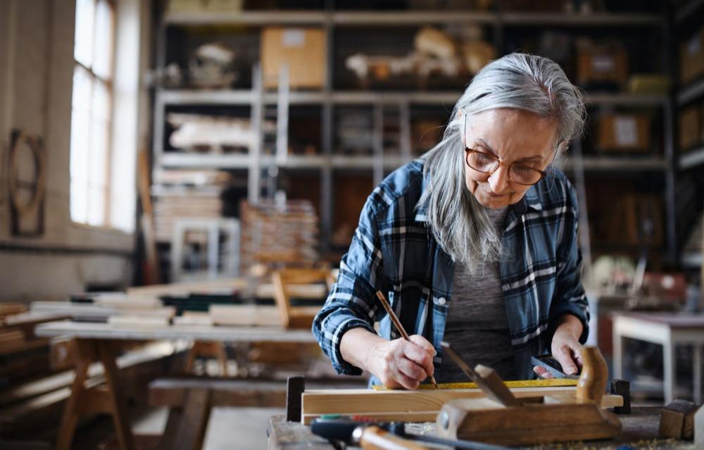 A professional measuring a woodworking project in a studio